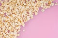 Popcorn scattered at half the pastel pink background and a space for copyspace. Popcorn on a red background Royalty Free Stock Photo