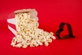 Popcorn spilled on blue background and film in heart form Royalty Free Stock Photo