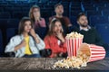 Popcorn on table and young people in cinema hall