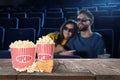 Popcorn, tickets on table and couple in cinema hall Royalty Free Stock Photo