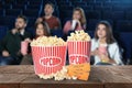 Popcorn, tickets on table and people in cinema hall Royalty Free Stock Photo