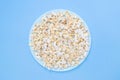 Popcorn on a turquoise plate for watching a movie. Blue background. Copy space. Flat lay. Top view. Quick and tasty