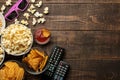 Popcorn and various snacks, 3D glasses, TV remote on a brown wooden background. concept of watching movies at home. top view with Royalty Free Stock Photo