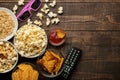 Popcorn and various snacks, 3D glasses, TV remote on a brown wooden background. concept of watching movies at home. view from abov Royalty Free Stock Photo