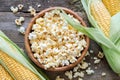 Popcorn in wooden bowl, corncobs on table. Top view.