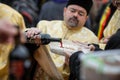 Shallow depth of field selective focus image with an orthodox priest pouring wine on a funeral cake during a ceremony