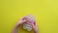 Popit antistress toy for children entertainment on a yellow background playing a child top view in colored fijit simple