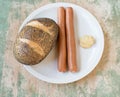 Poppy seed bun with vienna sausage and mustard on a plate Royalty Free Stock Photo