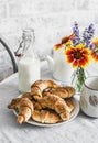 Poppy seeds croissants, bottle of milk, flowers on the kitchen table. Morning cozy home still life Royalty Free Stock Photo