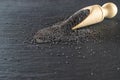 Poppy seeds isolated on dark stone background in wooden scoop. Pile poppyseed food in spoon on black. Healthy breakfast