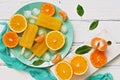 Popsicle orange with slices of fresh orange, mandarin and green leaves on a white rustic plank table. Top view, flat lay Royalty Free Stock Photo