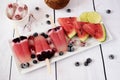 Popsicles with watermelon, coconut milk, lime, raspberries and blueberries. Popsicle on a white rectangular plateau, ice