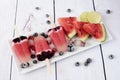 Popsicles with watermelon, coconut milk, lime, raspberries and blueberries. Popsicle on a white rectangular plateau, rectangle ice