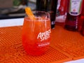 Popular Aperol Spritz cocktail in a glass with ice and orange on the bar table top