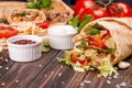 Popular arabic turkish fastfood doner shawarma roll with meat and vegetables and ingredients on wooden background. top view Royalty Free Stock Photo