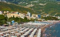 Popular beach of the resort of Becici is covered with beach umbrellas and crowds of tourists