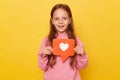 Popular child content, blogging. Portrait of charming preschool girl holding heart like icon of social media and looking at camera Royalty Free Stock Photo