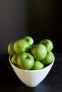 Green Granny Smith cooking apples in a white bowl against a brown background. Royalty Free Stock Photo