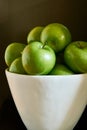 Green Granny Smith cooking apples in a white bowl against a brown background. Royalty Free Stock Photo