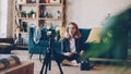 Popular female blogger is recording video about make-up and beauty sitting on floor at home and using camera on tripod Royalty Free Stock Photo