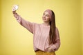 Popular glamour young female internet lifestyle blogger taking selfie on new smartphone extending arm taking picture