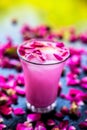 Popular Indian & Asian Summer drink on wooden surface i.e. Gulab falooda or gulab ka sherbat with some rose petals Royalty Free Stock Photo