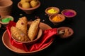 Popular Indian Sweet Besan Laddoo gram flour sweet balls and Gujia or Karanji arepopular Holi snacks served in earthen bowls.