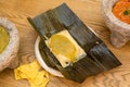 Popular Mexican chicken tamale in green sauce on banana leaf, with corn nachos