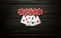 Popular poker game with a winning combination of three of a kind. Playing cards and red chips on a dark table in a poker club Royalty Free Stock Photo