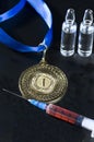 Popular red steroid in syringe and ampoules as a doping near a gold medal on a dark background