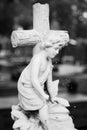 Porcelain child kneeling by a cross. Historic graveyard. Royalty Free Stock Photo