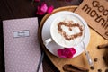 Porcelain cup of coffee with ice cream and cinnamon heart served at black wooden table with pink roses. life style concept