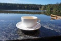 A porcelain cup of coffee that sits on the side of the balcony, with a magical view of the lake. Royalty Free Stock Photo