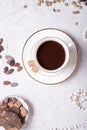 Porcelain cup of mocca coffee with natural chocolate, cocao beans, green coffe beans and neck beads around white provence