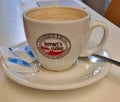 porcelain cup and saucer with sugar sachets and spoon with a half drunk coffee