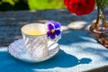 Porcelain cup of tea and beautiful spring flowers in vase on a wooden table in the garden. Summer party. Royalty Free Stock Photo