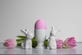 Porcelain Egg Cups with pink Easter egg and porcelain Easter bunnies and same pastel colored pink white tulips Royalty Free Stock Photo