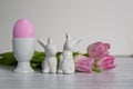 Porcelain Egg Cups with pink Easter egg and porcelain Easter bunnies and same pastel colored pink white tulips Royalty Free Stock Photo