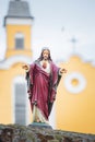 Porcelain figurine of Jesus on the background of the facade of the church