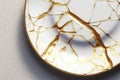 Porcelain Kintsugi plate on a white table. The antique restoration method. Repair gold cracks in old Japanese pottery. Unique