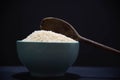 Porcelain pan with raw white rice and wooden spoon on black background Royalty Free Stock Photo