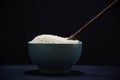 Porcelain pan with raw white rice and wooden spoon on black background Royalty Free Stock Photo