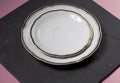 Porcelain plate and saucer of white color with a gold border on a black background. Royalty Free Stock Photo