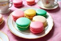 A plate of colorful macarons with tea cups.