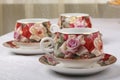 Porcelain tea cups with saucers and floral pattern on a table with white tablecloth Royalty Free Stock Photo