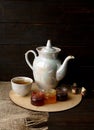 Porcelain tea kettle and teacup with green tea. Pressed roses on a wooden table. Three small jars of homemade berry jam on the woo Royalty Free Stock Photo