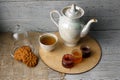 Porcelain tea kettle and teacup with green tea. Pressed roses on a wooden table. Three small jars of homemade berry jam on the woo Royalty Free Stock Photo