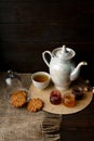 Porcelain tea kettle and teacup with green tea. Pressed roses on a wooden table. Three small jars of homemade berry jam on the woo Royalty Free Stock Photo