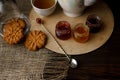 Porcelain tea kettle and teacup with green tea. Pressed roses on a wooden table. Three small jars of homemade berry jam on the woo Royalty Free Stock Photo