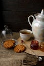 Porcelain tea kettle and teacup with green tea. Pressed roses on a wooden table. Three small jars of homemade berry jam on the woo Royalty Free Stock Photo